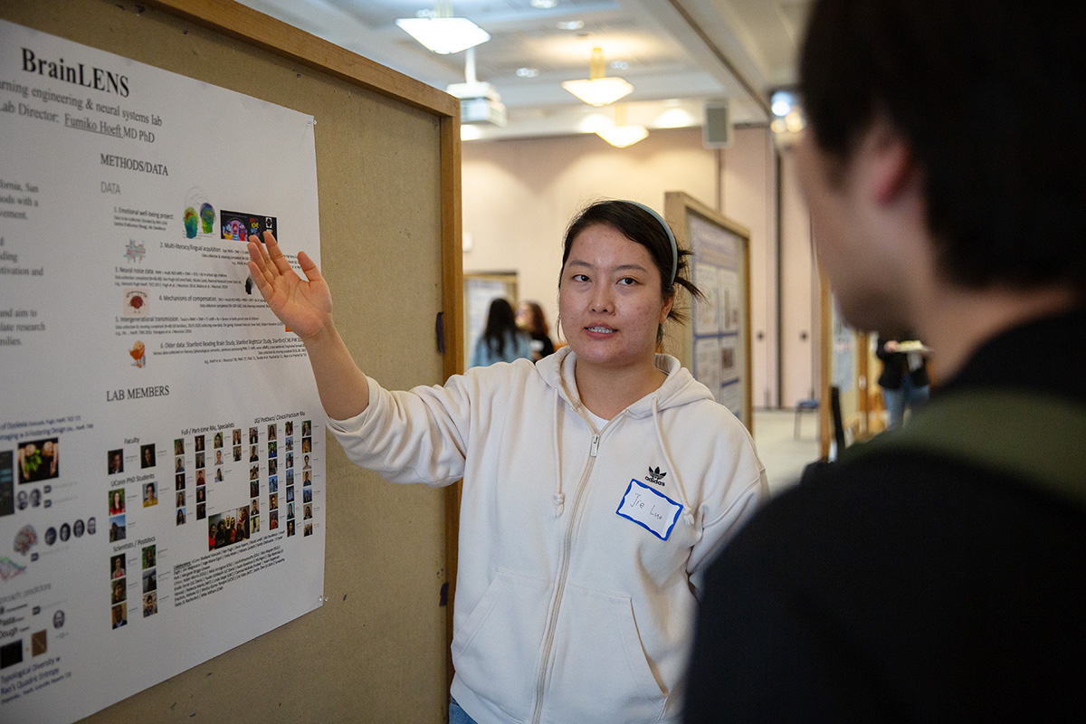 A student presents research at a poster presentation event.